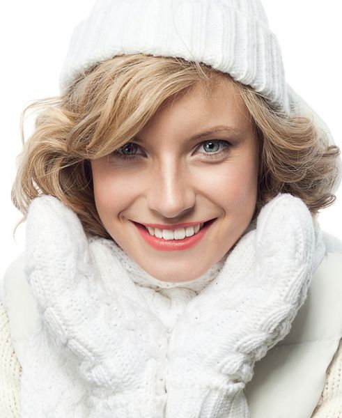 زن جوان قفقازی جذاب با لباس گرم در استودیو جدا شده روی سفید لبخند می زند