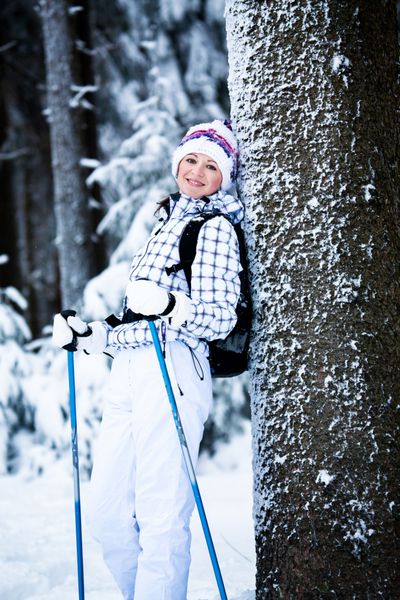 زن جوان در حال پیاده روی در یک جنگل برفی
