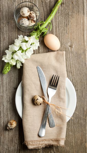 چیدمان میز عید پاک با گل و تخم مرغ روی میز چوبی قدیمی