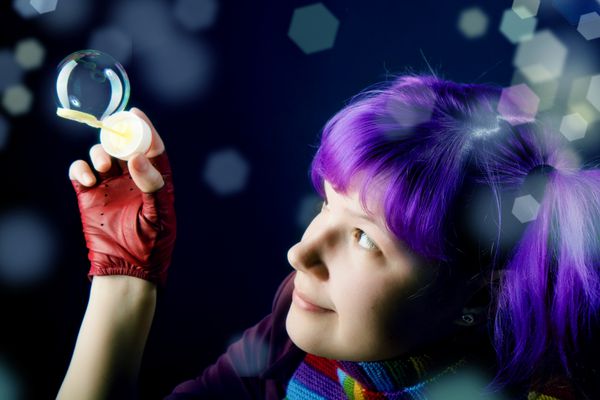 دختری با موهای بنفش که با حباب های صابون بازی می کند