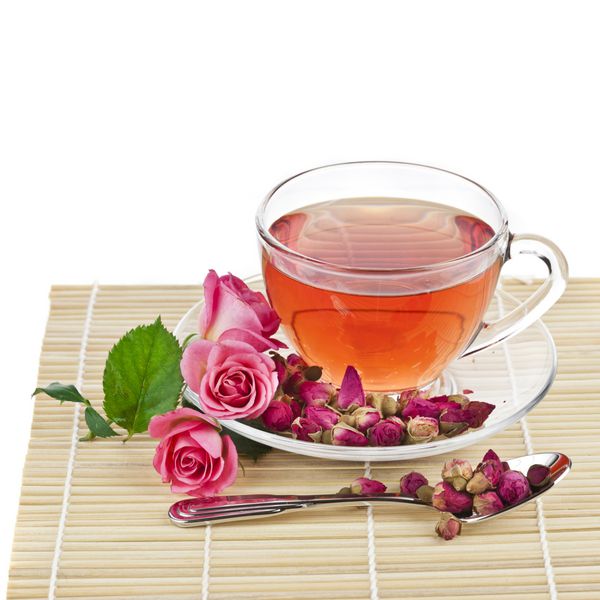 فنجان لیوان چای با گل رز تازه جدا شده روی سفید