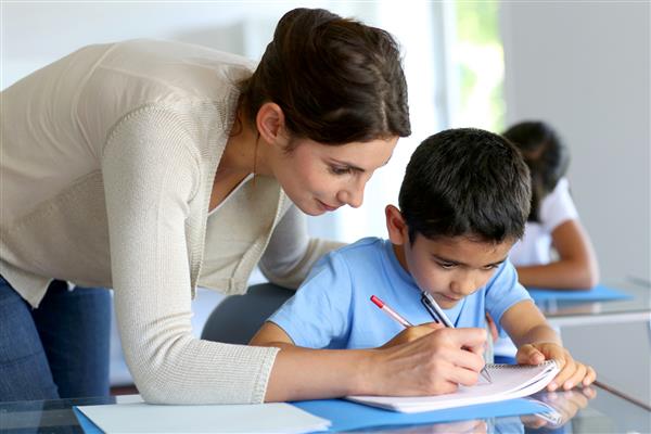 معلمی که به پسر جوان در درس نوشتن کمک می کند