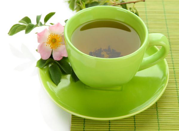 فنجان چای گیاهی با گل رز باسن جدا شده روی سفید