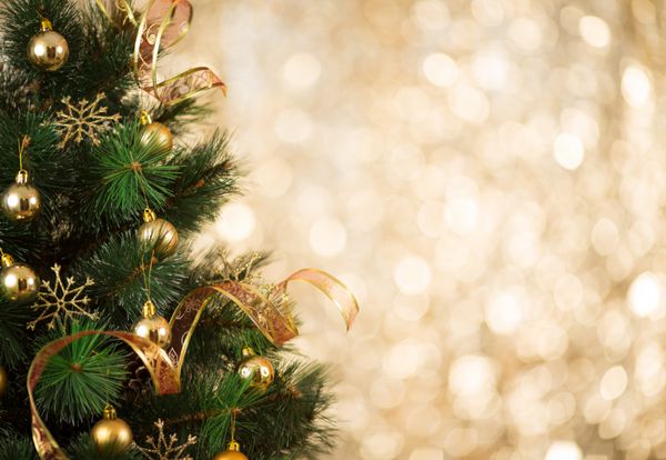 پس‌زمینه طلایی کریسمس از چراغ‌های بدون تمرکز با درخت تزئین شده