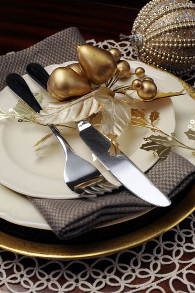 جدیدترین ترند میز شام رسمی کریسمس تم متالیک طلایی با ظروف چینی استخوانی ظریف چوب دستی و تزئینات جشن از نزدیک روی کارد و چنگال و بشقاب