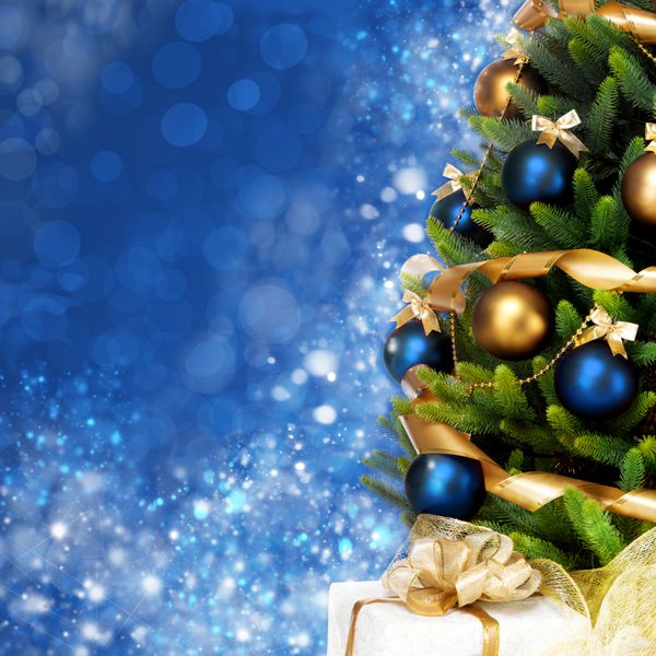 درخت کریسمس با توپ‌ها روبان‌ها و گلدسته‌هایی که به‌طور جادویی تزئین شده‌اند روی پس‌زمینه آبی براق پری و درخشان