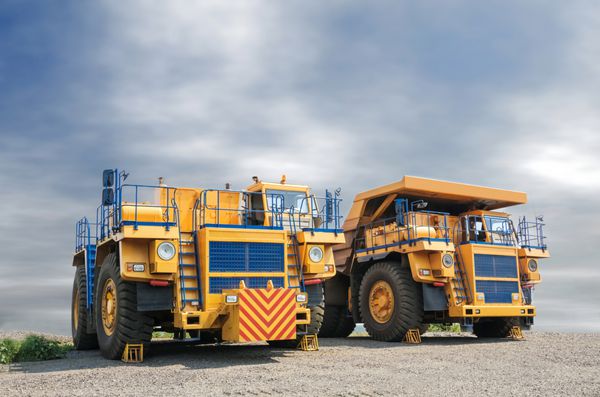 بیل مکانیکی بزرگ زرد رنگ استخراج سنگ آهن در معدن روباز و بارگیری کامیون سنگین
