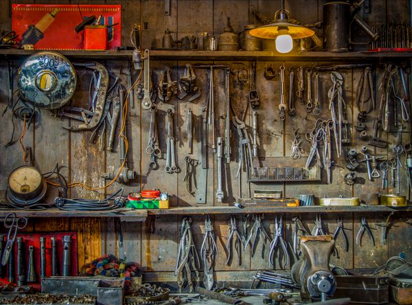 ابزارهای قدیمی آویزان روی دیوار در سوله ابزار یا کارگاه