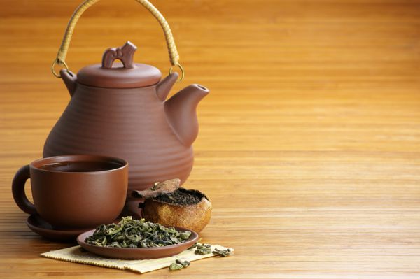 چای خشک فنجان چای و قوری روی زمینه چوبی با فضای کپی