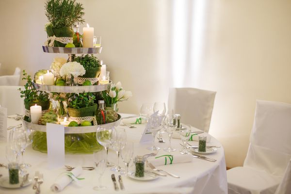 چیدمان میز زیبا برای جشن عروسی یا جشن سبز رنگ در داخل خانه با چیدمان گل و شمع بزرگ