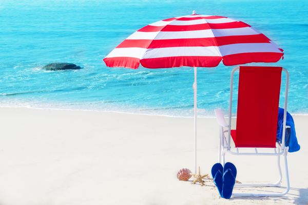 چتر ساحلی و صندلی کنار اقیانوس در روز آفتابی