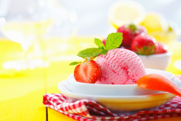 بستنی توت فرنگی استوایی با توت فرنگی رسیده تازه در یک محیط رومیزی در تعطیلات تابستانی سرو می شود