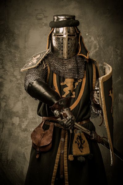 شوالیه قرون وسطایی با شمشیر و سپر در برابر دیوار سنگی