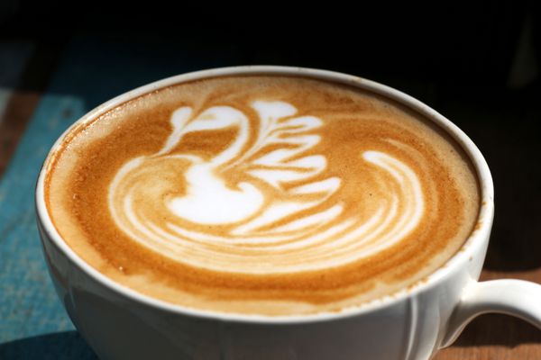 از نزدیک قهوه کاپوچینو روی میز با صورت پرنده