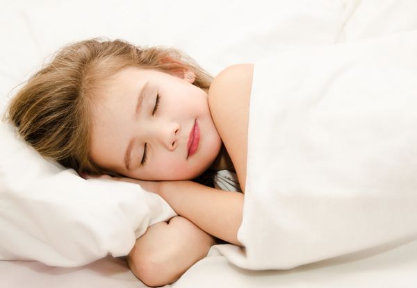 دختر کوچولوی دوست داشتنی که روی تخت می خوابد