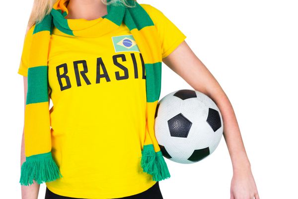هوادار فوتبال با تی شرت برزیلی که توپ را در پس زمینه سفید نگه می دارد