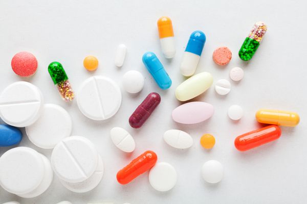 بسیاری از داروهای رنگارنگ قرص و کپسول در زمینه سفید