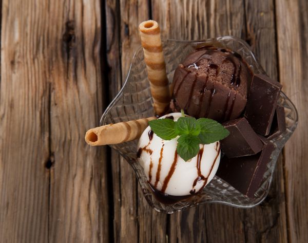 بستنی شکلاتی و وانیلی دمنوش تابستانی با میوه های تازه در زمینه چوبی