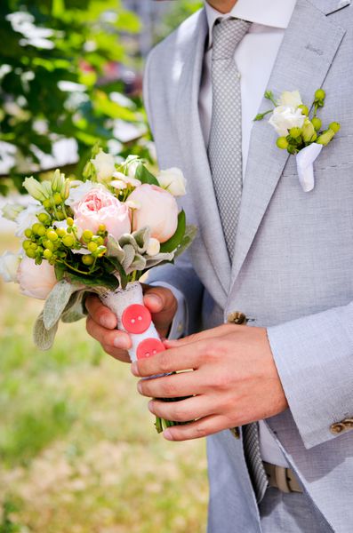 داماد با کت و شلوار خاکستری با دسته گل عروسی