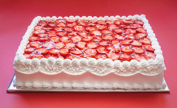 کیک تولد با توت فرنگی در پس زمینه قرمز