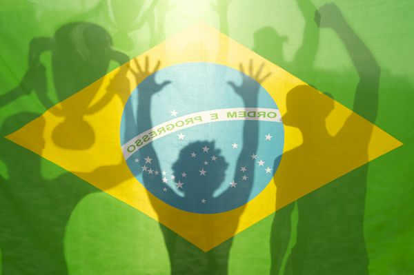 بازیکنان فوتبال پرچم برزیل سایه‌هایی را که در حال جشن گرفتن جام قهرمانی در برابر نور درخشان خورشید هستند جشن می‌گیرند