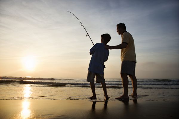 ماهیگیری پدر و پسر در موج سواری اقیانوس در غروب آفتاب