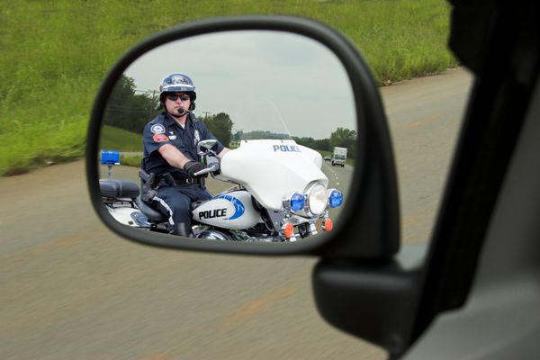 افسر پلیس سوار بر موتور سیکلت خود که مراقب رانندگان تندرو است پشت وسیله نقلیه ای که به سرعت در حال حرکت است می آید