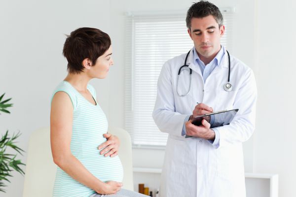 زن باردار در حال صحبت با پزشکش در اتاق
