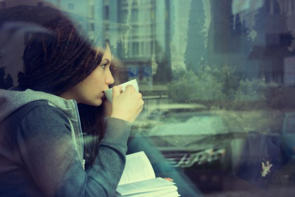زن جوان در حال نوشیدن قهوه و کتاب خواندن در داخل کافه شهری نشسته است سبک زندگی کافه سیتی پرتره گاه به گاه دختر نوجوان پررنگ