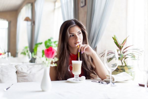 یک زن خندان در یک رستوران در حال نوشیدن کوکتل است