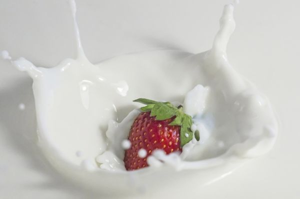 تصویر نزدیک از پاشیدن توت فرنگی در شیر