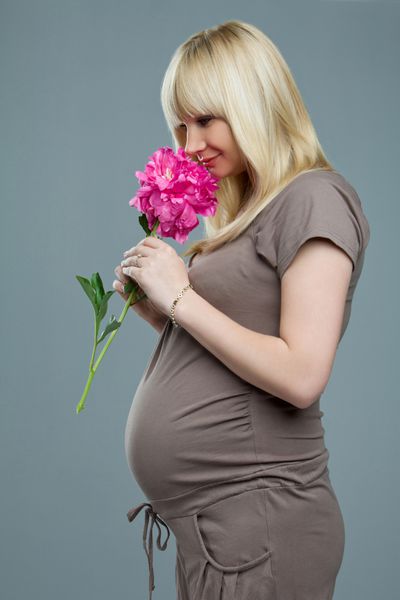زن باردار با بوی گل پرتره زن باردار در لباس با بوی گل قرمز