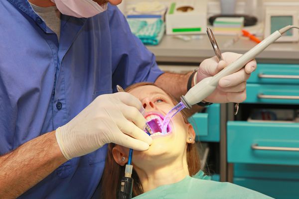 نور درمان دندان در دهان دختر در مطب دندانپزشکی