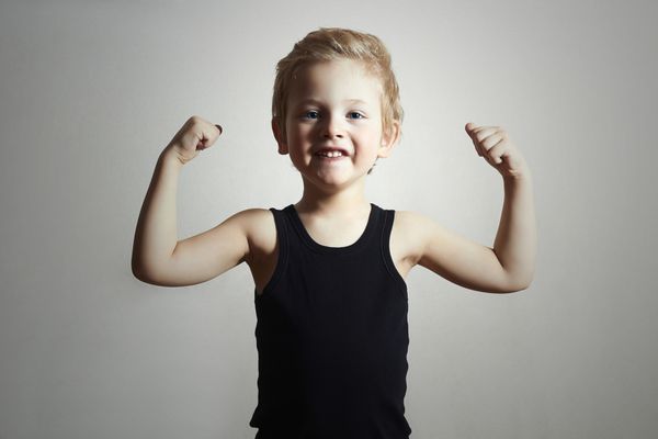 کودک پسر کوچولوی خنده دار پسر خوشتیپ اسپورت قوی بدنساز عضلات دوسر دستش را نشان می دهد