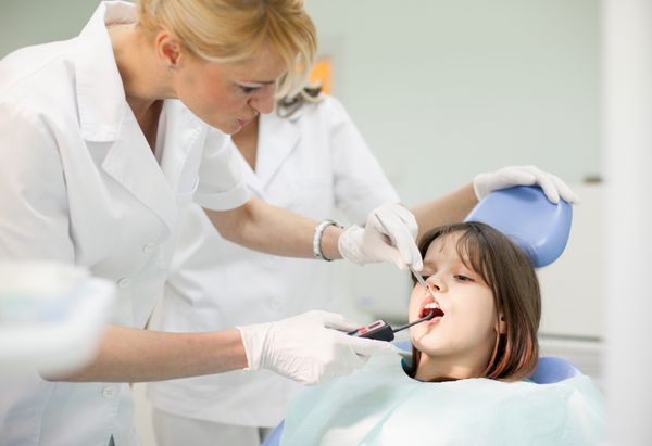 کار تیمی دندانپزشکی زن دندانپزشک و دختر جوان خندان در دندانپزشک