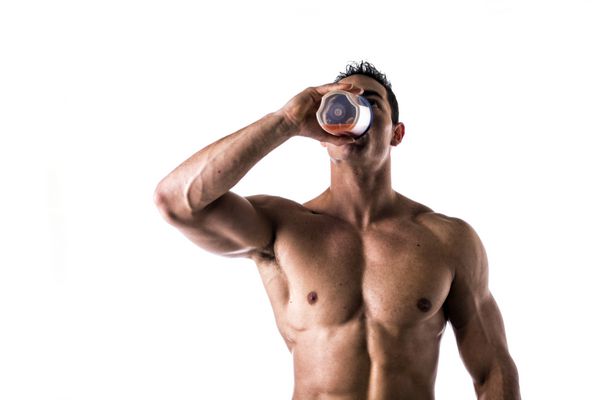بدنساز مرد بدون پیراهن عضلانی در حال نوشیدن شیک پروتئینی از مخلوط کن جدا شده روی سفید به بالا نگاه می کند