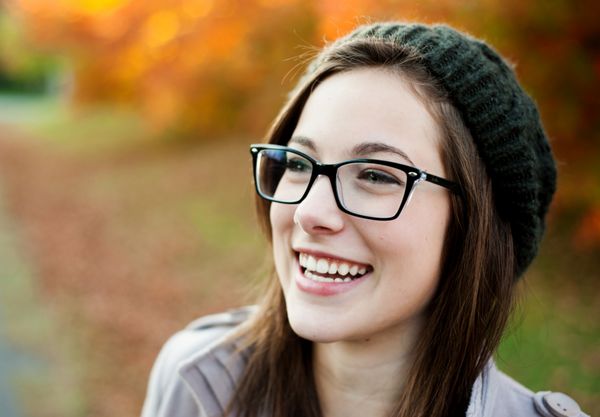زن جوانی با عینک در پاییز می خندد