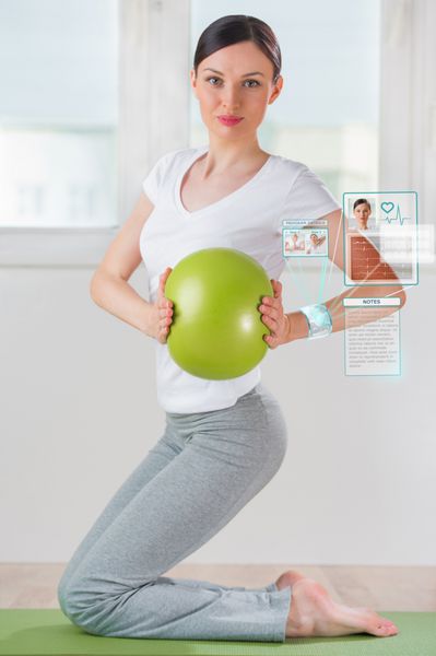 زنی در حال انجام ورزش با توپ با پوشیدن دستگاه پوشیدنی هوشمند با رابط آینده نگر
