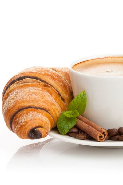 فنجان قهوه با دانه های قهوه چوب دارچین و کروسان شکلاتی در زمینه سفید