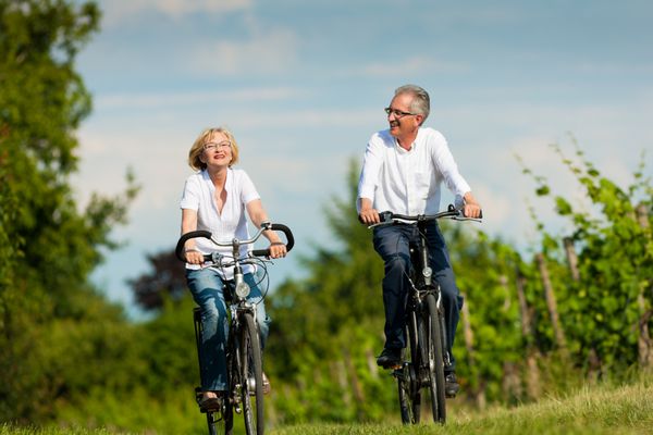 زوج بالغ خوشحال افراد مسن زن و مرد که قبلاً بازنشسته شده اند در تابستان در طبیعت دوچرخه سواری می کنند