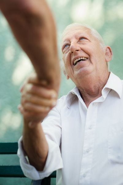بازنشستگی فعال دو دوست مرد قدیمی در حال صحبت و دست دادن روی نیمکت در پارک عمومی