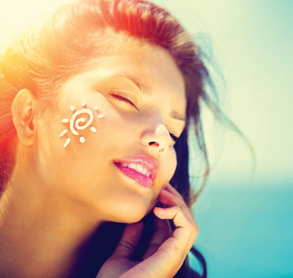لوسیون ضد آفتاب زنانه در حال استفاده از کرم ضد آفتاب خورشیدی دختر زیبای شاد و بامزه ای که از کرم ضد آفتاب برنزه روی صورت خود روی پس زمینه اقیانوس استفاده می کند برنزه شدن آفتاب مراقبت و محافظت از پوست تعطیلات