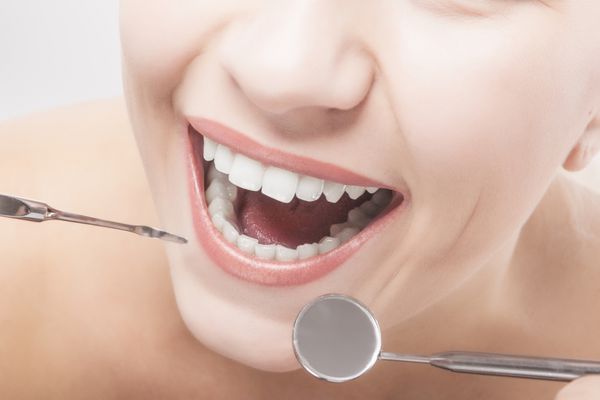 نمای نزدیک از دندان های زن با ابزارهای دندانپزشکی تصویر افقی