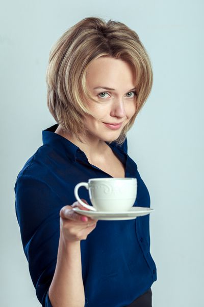 زن خندان با فنجان قهوه یا چای استراحت کن