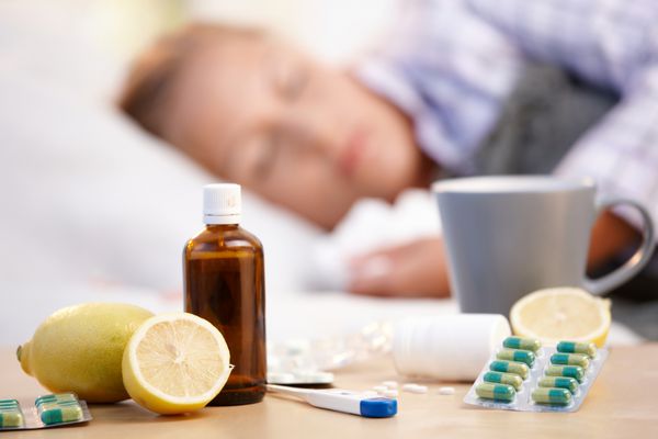ویتامین ها داروها و چای داغ جلو زن سرد خواب در پس زمینه