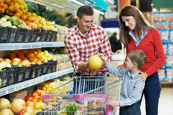 زن با مرد و کودکی که میوه خربزه را هنگام خرید از سوپرمارکت سبزیجات انتخاب می کند