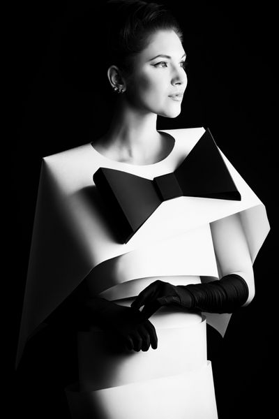 عکس مد هنری از یک زن زیبا با لباس کاغذی سیاه و سفید