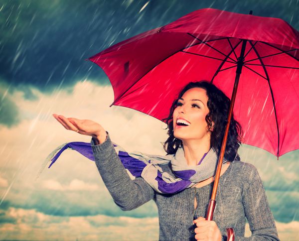 زن خندان با چتر بر روی پس زمینه باران پاییزی خندیدن دختر سالم در فضای باز هوای بد