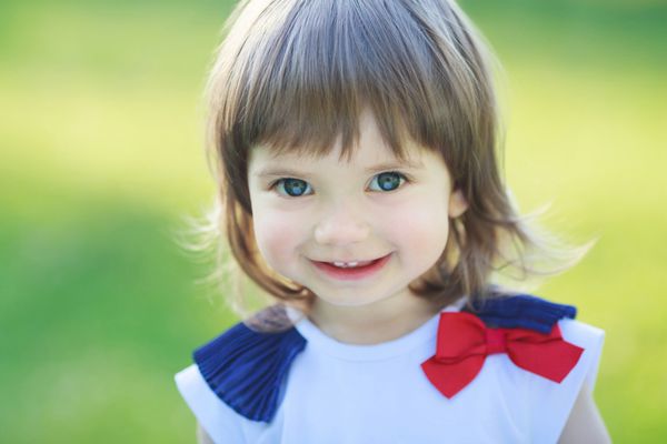 دختر کوچک زیبا که در یک روز آفتابی لبخند می زند