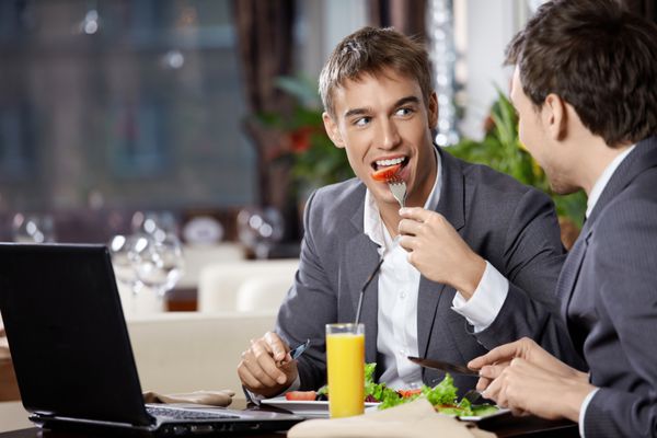 دو تاجر خندان در رستوران غذا می خورند